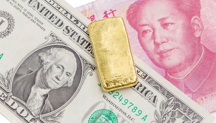 Lingote de oro sobre billetes de dólar y yuan