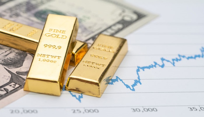 Lingotes de oro y dólares sobre un gráfico