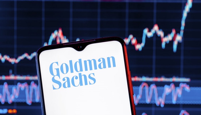 Móvil con logo de Goldman Sachs y gráfico de fondo